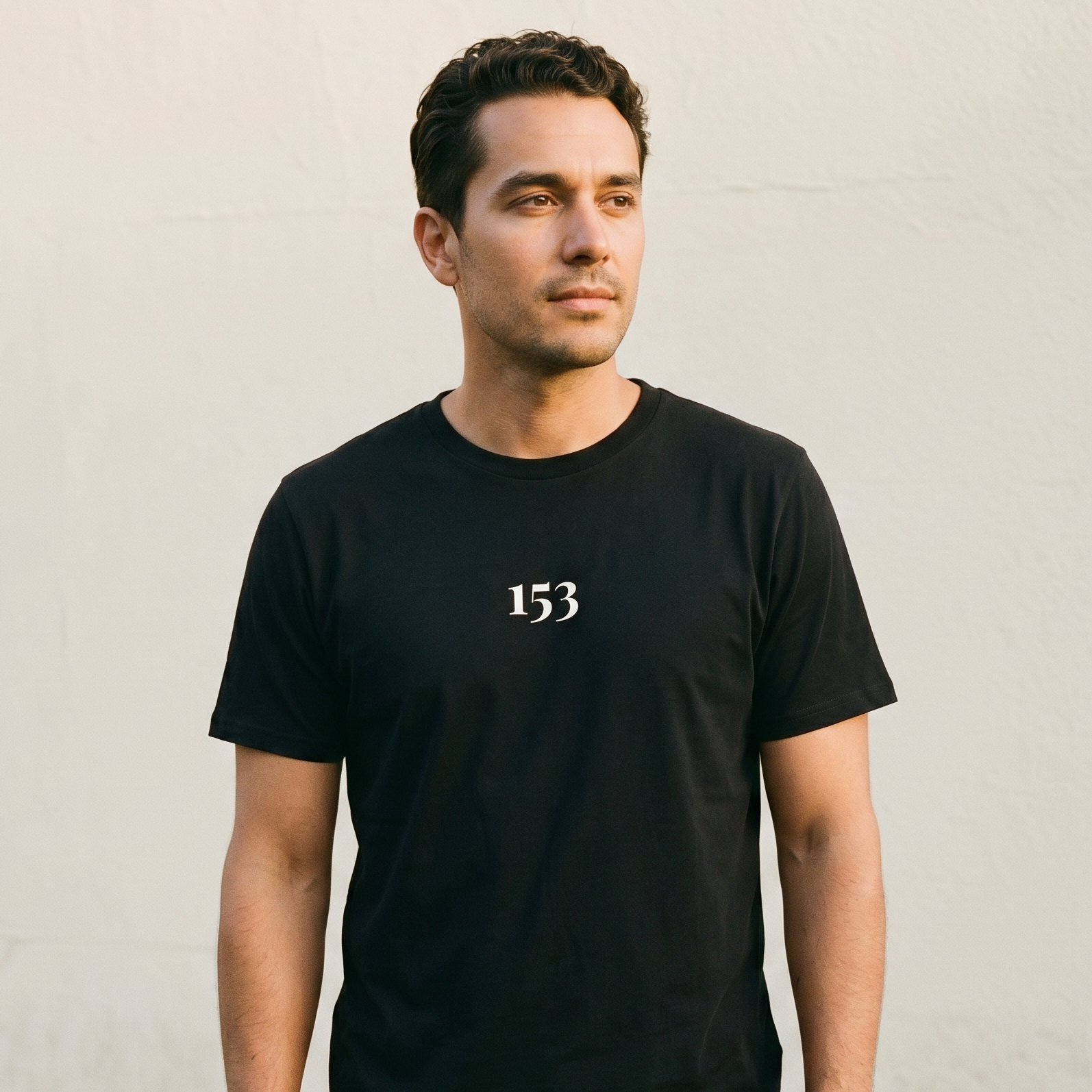 Man wearing a black t-shirt with the number 153 on a plain background