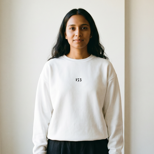 Person wearing a white sweatshirt with a 153 logo, standing against a plain wall.