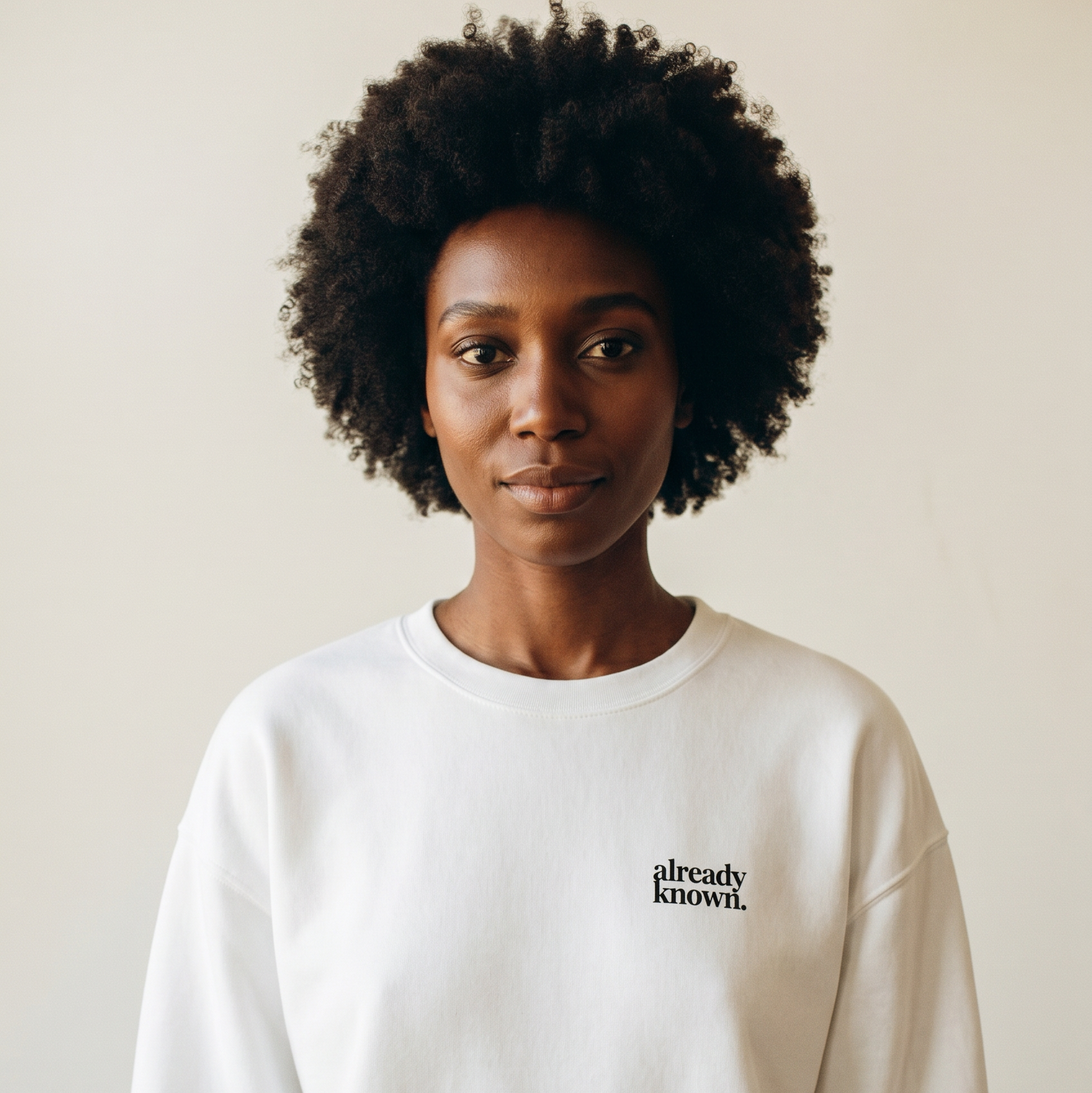 Person wearing a white sweatshirt with 'already known' text on a plain background