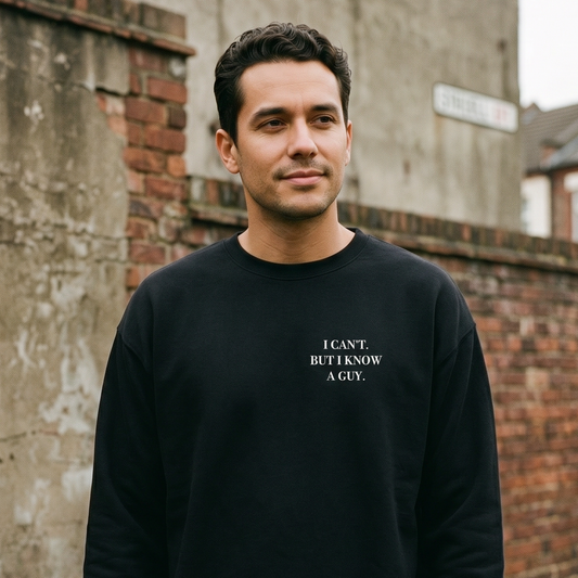 Man wearing a black sweatshirt with text standing against a brick wall.