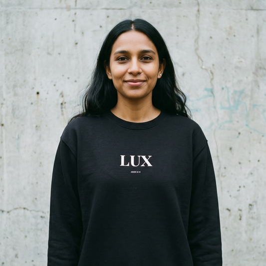 Person wearing a black sweatshirt with 'LUX' logo against a concrete wall.