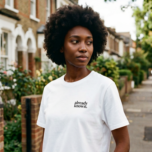 Person wearing a white t-shirt with 'already known' text on a residential street.