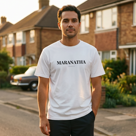Man wearing a white t-shirt with 'MARANATHA' printed on it, standing on a residential street.