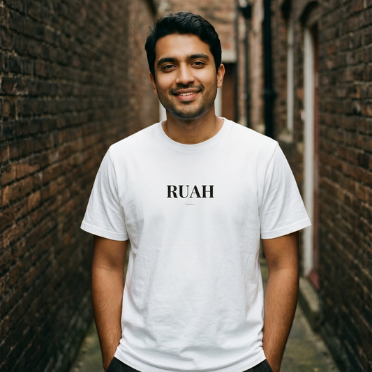 Man wearing a white 'RUAH' t-shirt standing in a narrow alley with brick walls.