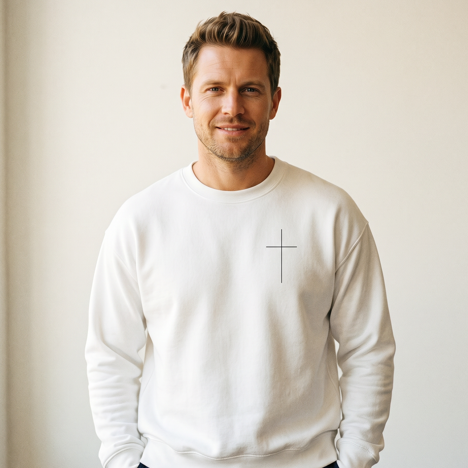 Man wearing a white sweatshirt with a cross design against a plain background